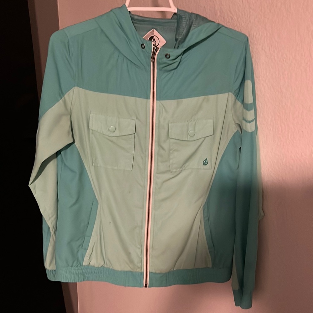 Light, windbreaker, teal jacket. Full zip. Hooded.